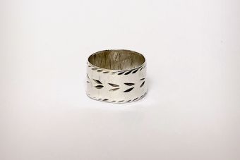 Silver ring with markings on a plain background